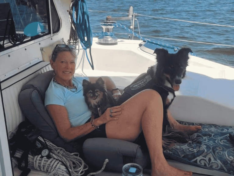 woman with two dogs lounging on sailboat deck on private cruise