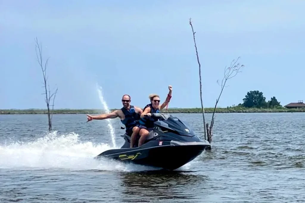 Couple waving while riding a jet ski across Roanoke Sound on a guided tour