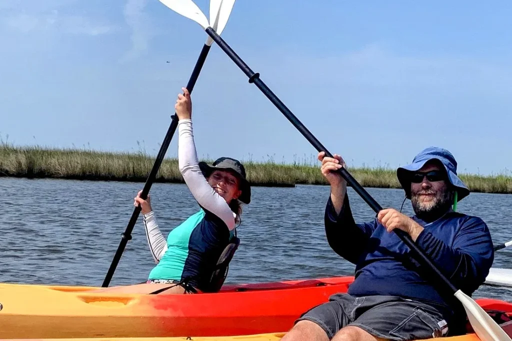 Two paddlers raising their paddles in kayaks on Roanoke Sound