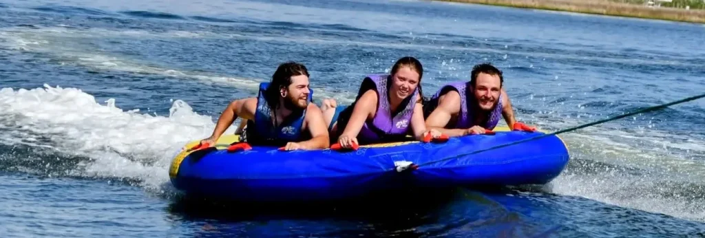 Three tubers laughing as they ride across Roanoke Sound