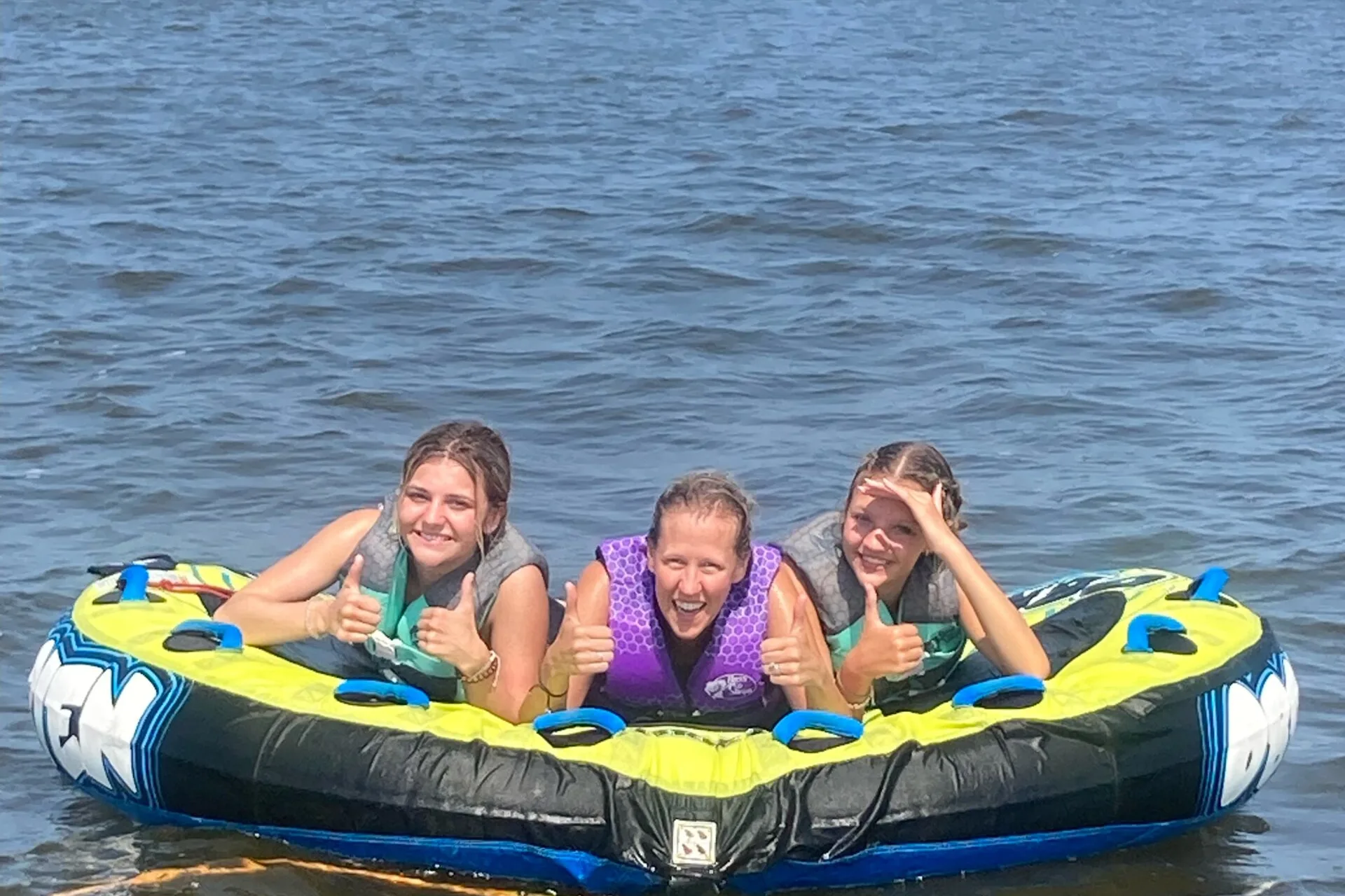 Three girls relaxing on a towable tube on calm water