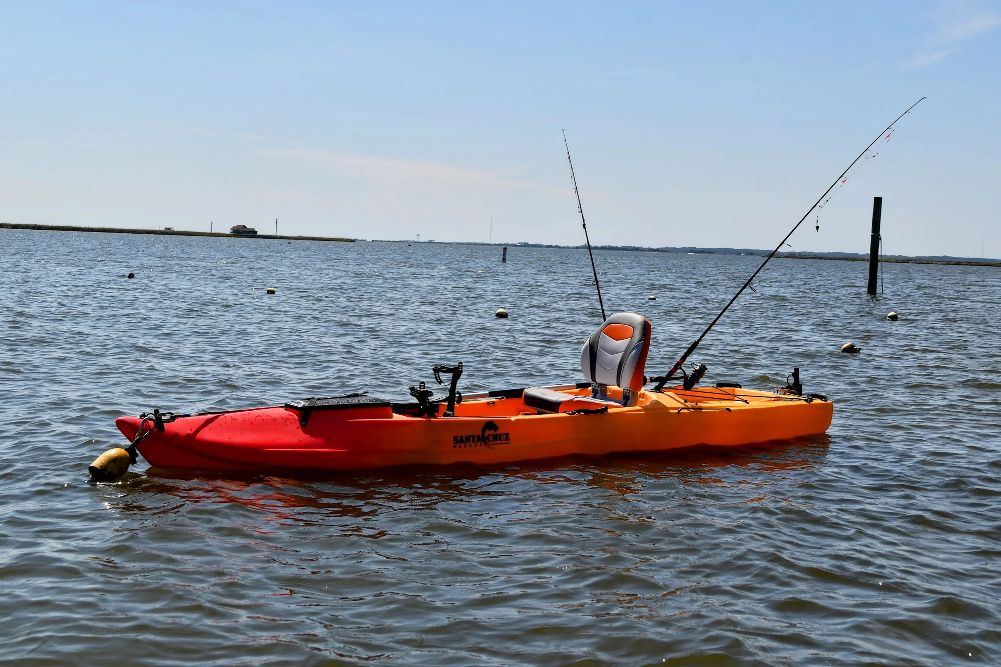 Fishing kayak rigged with rod holders on calm water