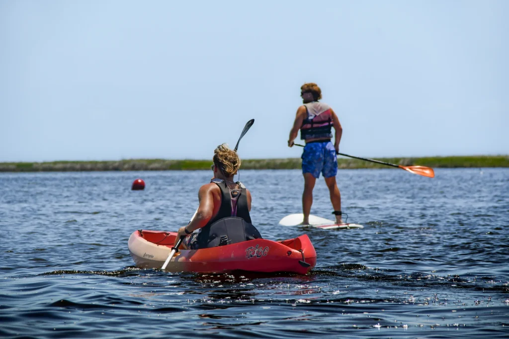 Woman on a stand up paddleboard beside a kid in a kayak in Nags Head