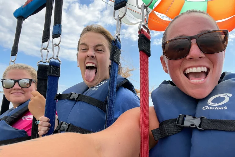Smiling parasailers taking a mid-air selfie during an Outer Banks flight