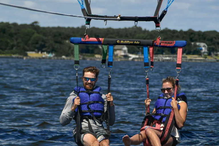Three riders parasailing side by side above Roanoke Sound