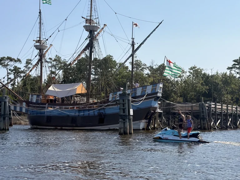 Jet ski riders passing a historic tall ship on the sound