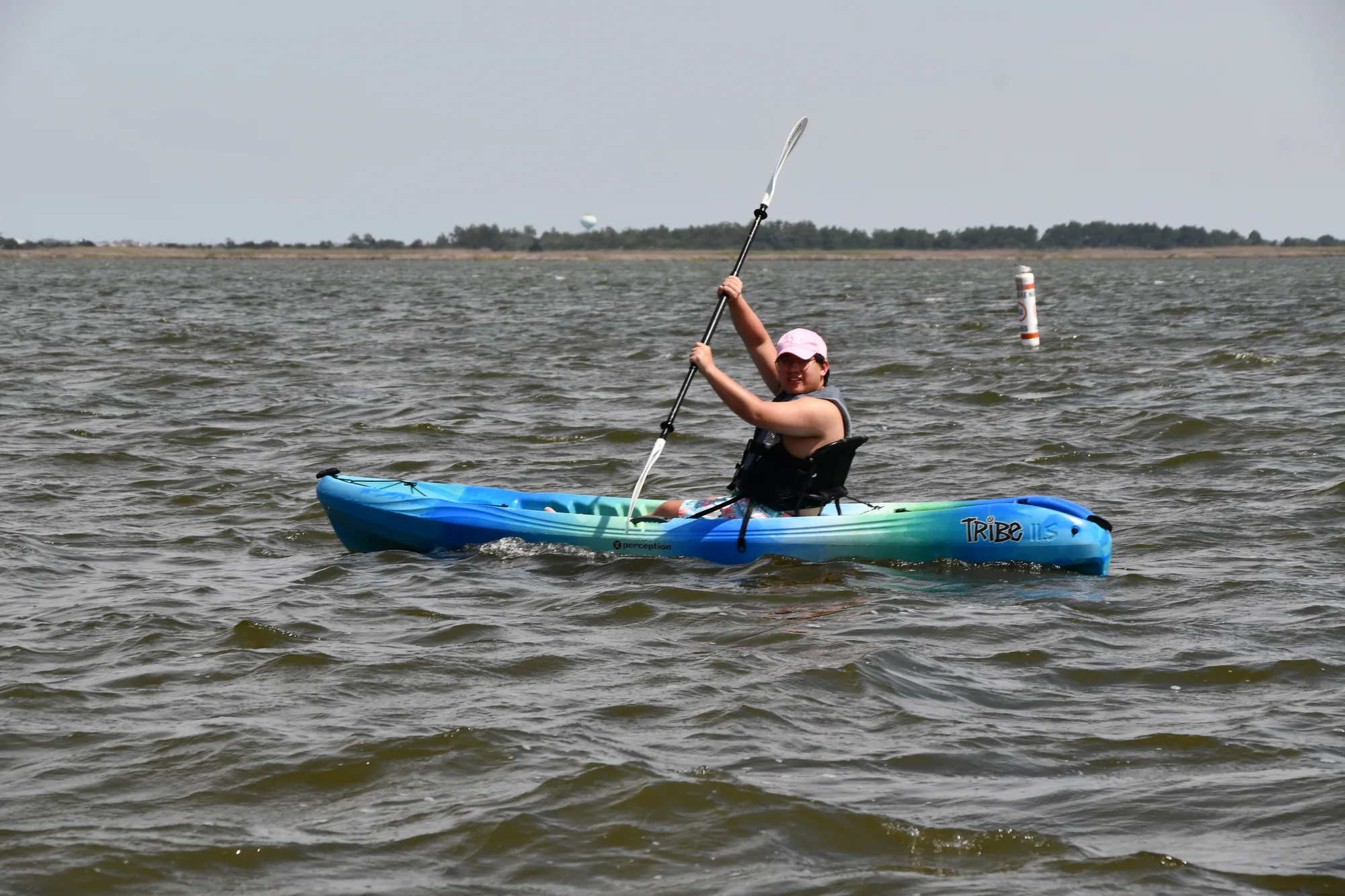 Paddler raising a paddle in a single kayak on the sound