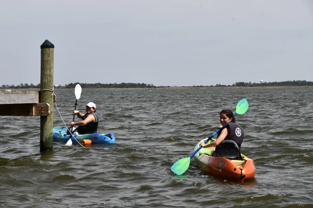 Two paddlers in colorful kayaks on the sound