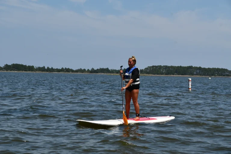 Guest paddling a stand-up paddleboard on calm water