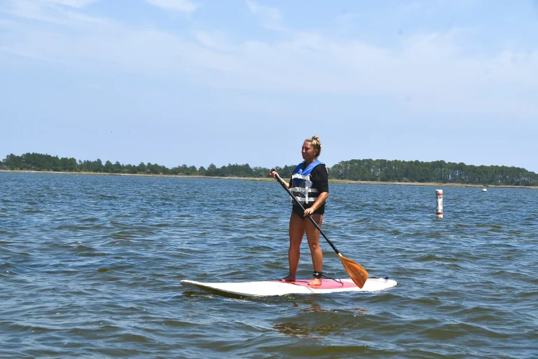 Guest standing on a paddleboard with paddle on the sound