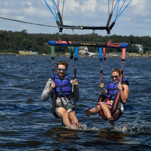 A couple taking a refreshing dip in the water while parasailing on a hot day in the Outer Banks NC.