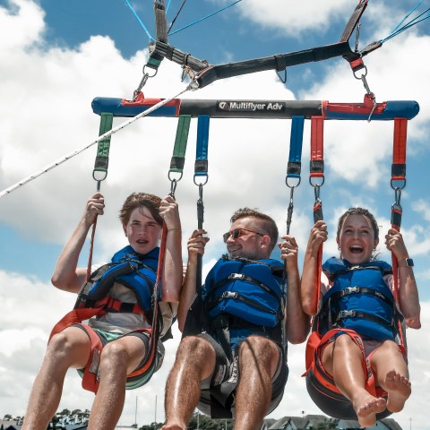 Three people having an exciting time parasailing with Causeway Watersports in Nags Head.