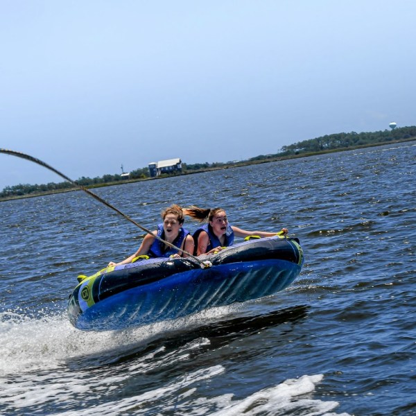 Two girls try to hang on during their exciting tubing trip in Nags Head, with Causeway Watersports.