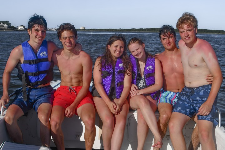 A group of kids poising on the front of Causeway Watersports tubing boat.