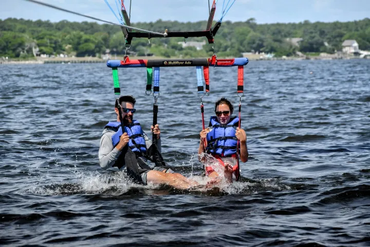 A couple getting a refreshing dip in the water while parasailing on a hot day in the Outer Banks NC.