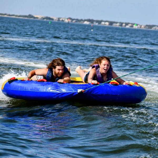 A young couple try to hold onto the tube they are riding.