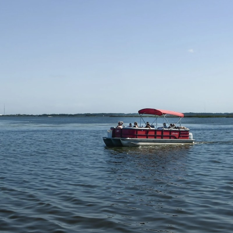 A group on a pontoon boat enjoying time on the calm waters of Nags Head while on their vacation in the Outer Banks.