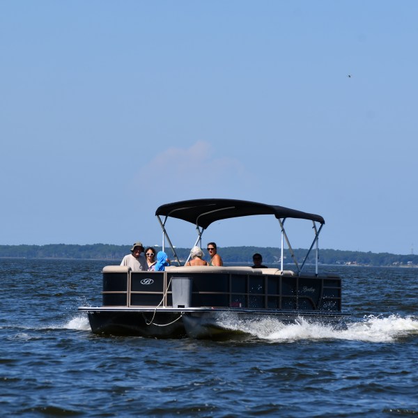 A group of people on a pontoon boat cruising on a lake.